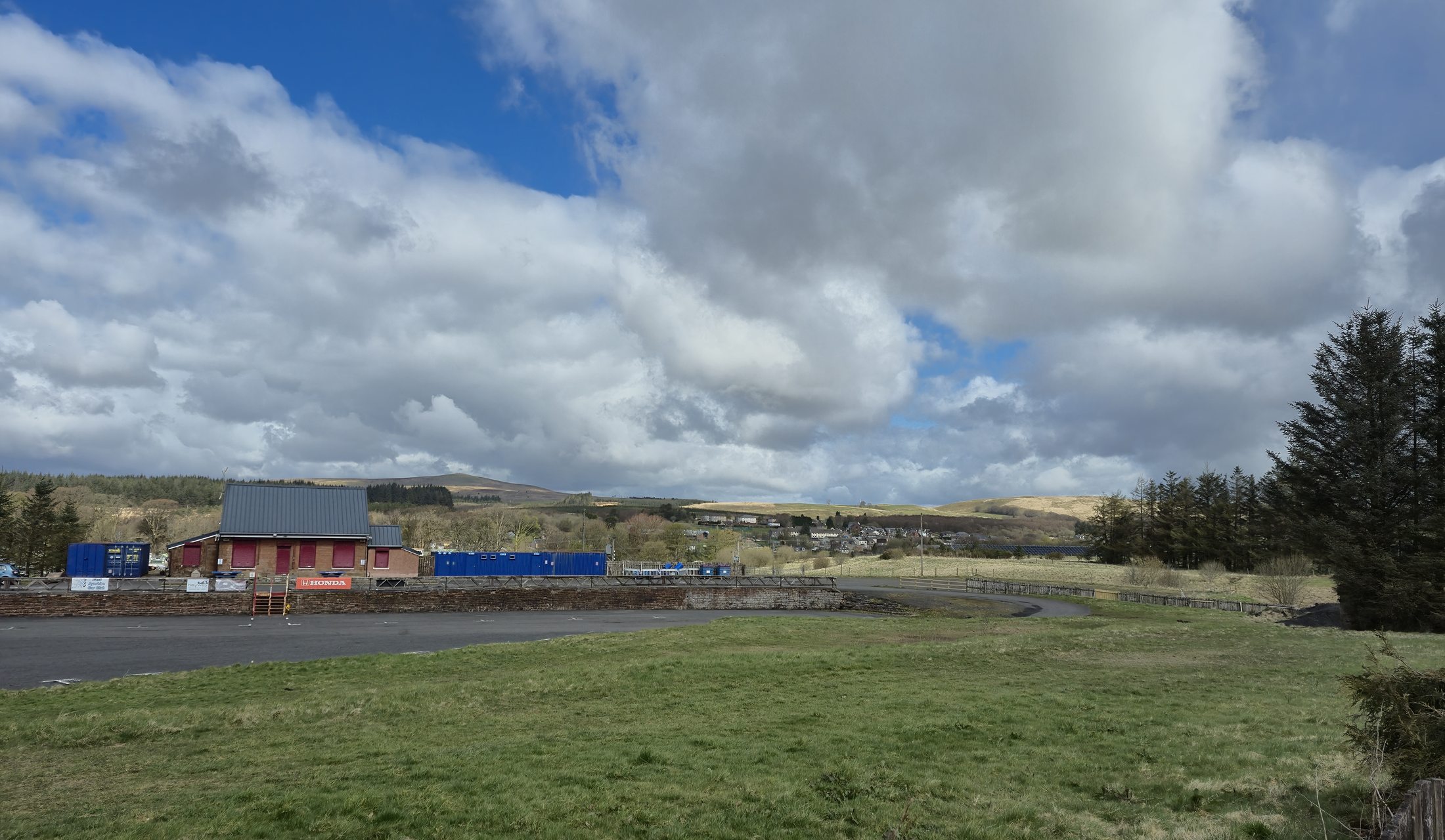A wide view across Muirkirk and the surrounding hills under a bright clouded sky.